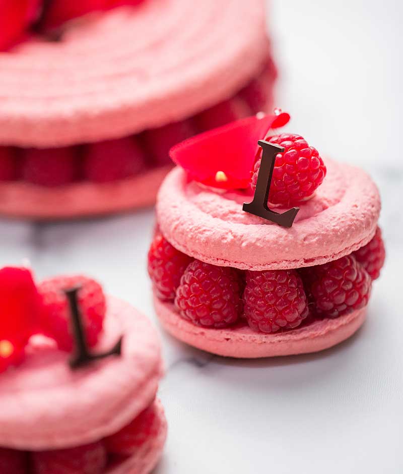 Rose macaron topped with rose-scented cream, garnished with fresh raspberries and lychees. A subtle combination of the acidity of lychee and the sweetness of raspberry and rose. A delicious, fresh, gourmet dessert.
