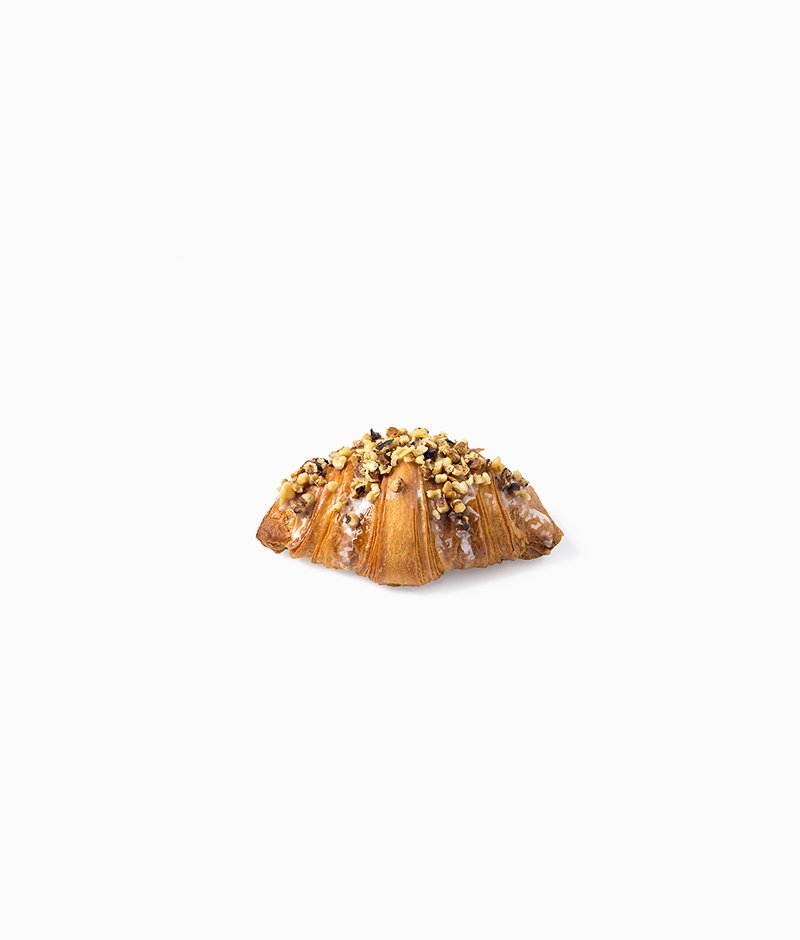 A gourmet croissant: puff pastry filled with walnut paste, sweetened with hazelnuts and almonds and decorated with a sugar glaze. All viennoiserie is served with a small napkin.