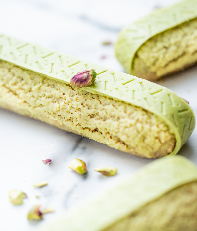 Choux pastry with a creamy pistachio filling and a pistachio praline insert, decorated with a strip of pistachio chocolate.